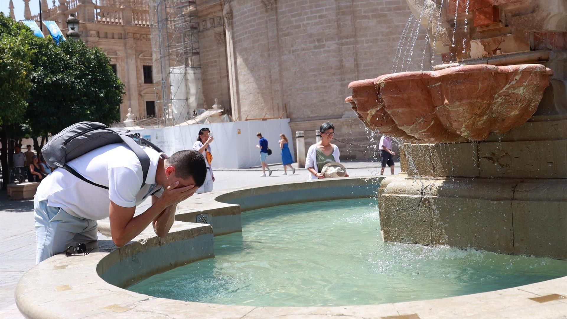 Un joven se refresca en una fuente para soportar las altas temperaturas en Sevilla (archivo)