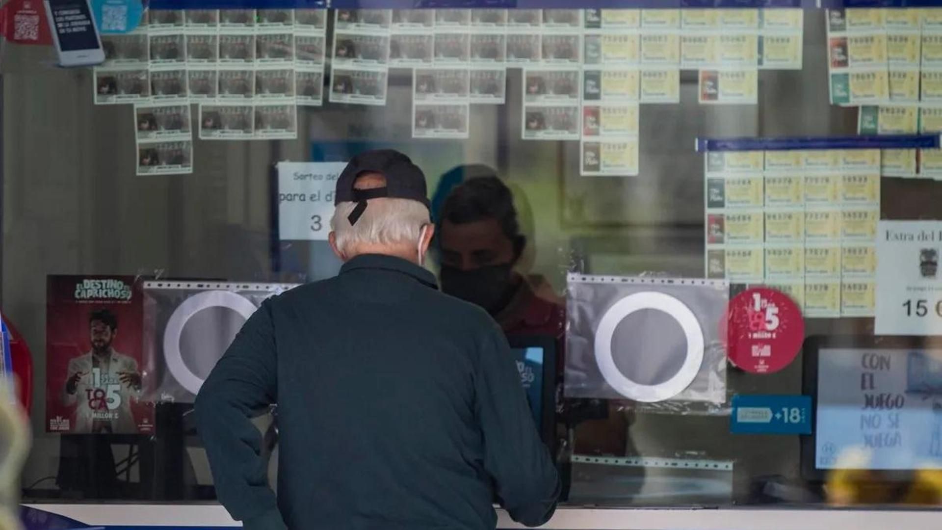 Una persona compra loteria en una administracion