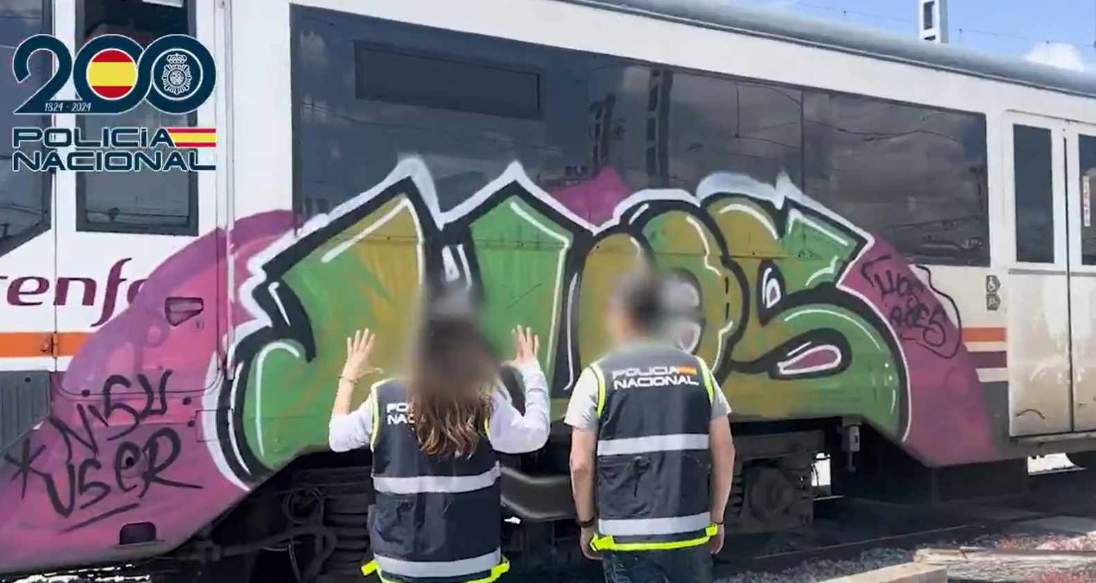 Agentes frente a un tren vandalizado con grafitis