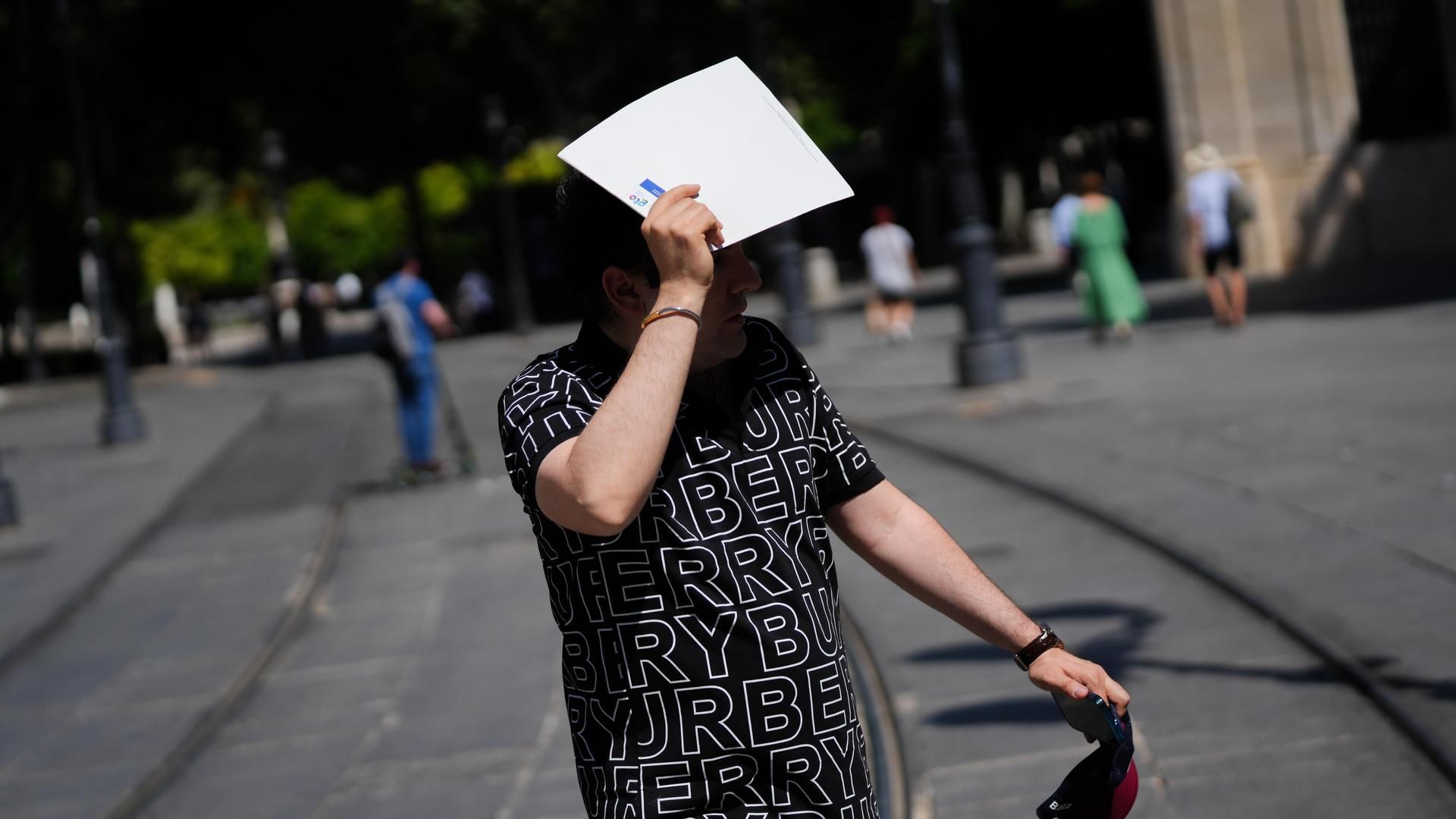 Imagen de archivo de un hombre protegiéndose del sol en las calles de Sevilla Imagen de archivo de un hombre protegiéndose del sol en las calles de Sevilla