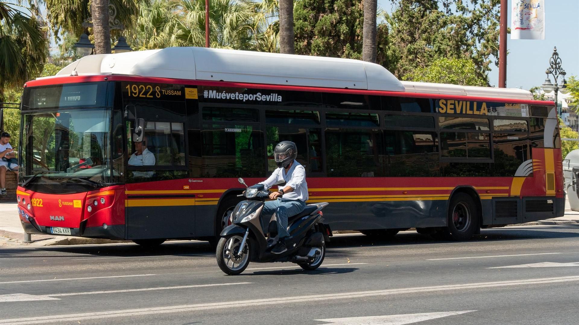Una motocicleta circula junto a un autobús de Tussam en el Paseo de Colón de Sevilla
