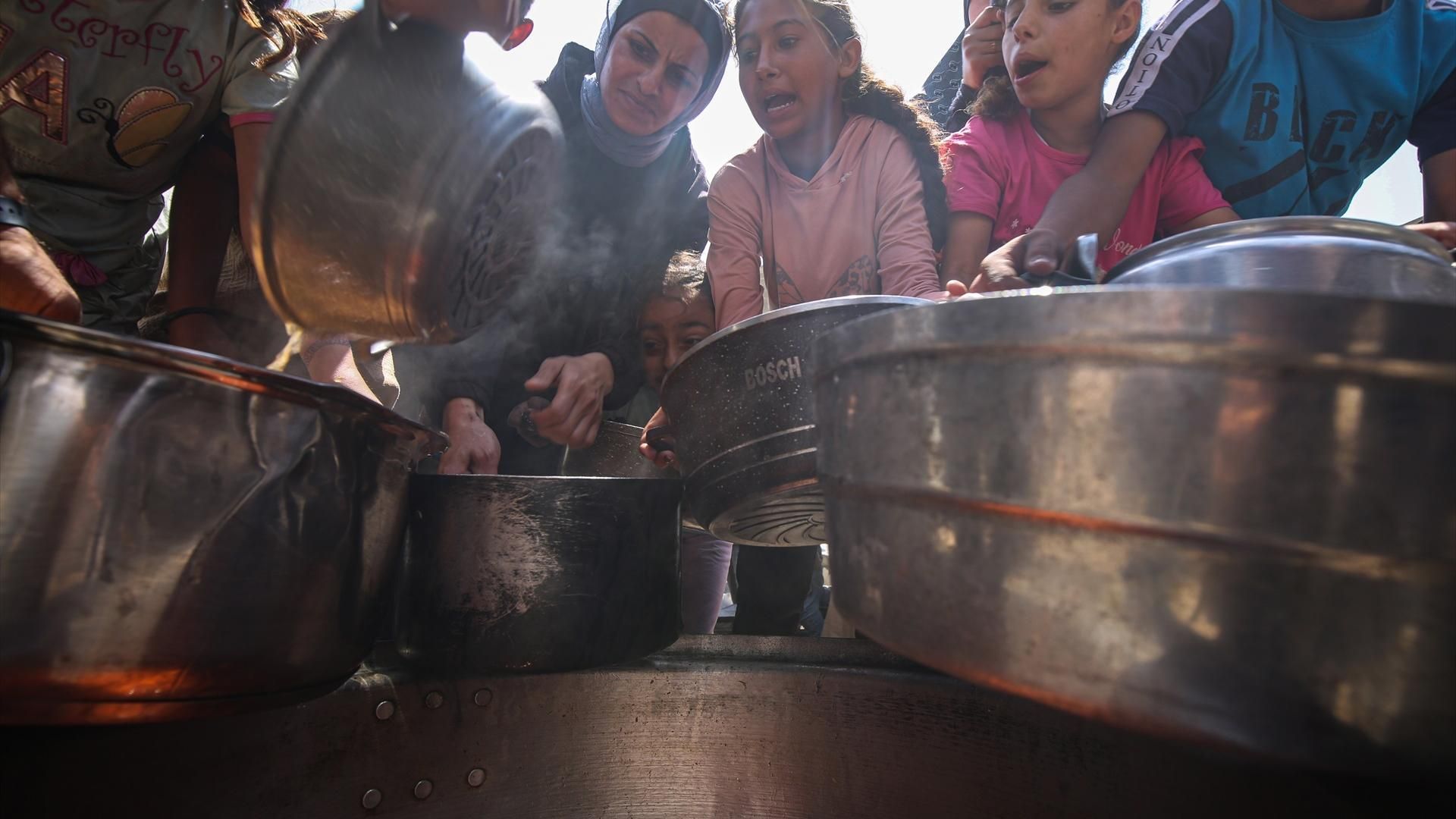 Un grupo de niños palestinos reciben alimentos en Gaza.