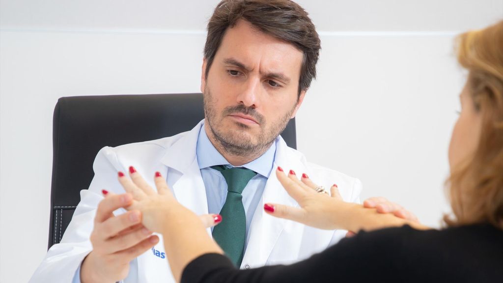 Un médico evalúa el temblor de una paciente de párkinson en consulta.