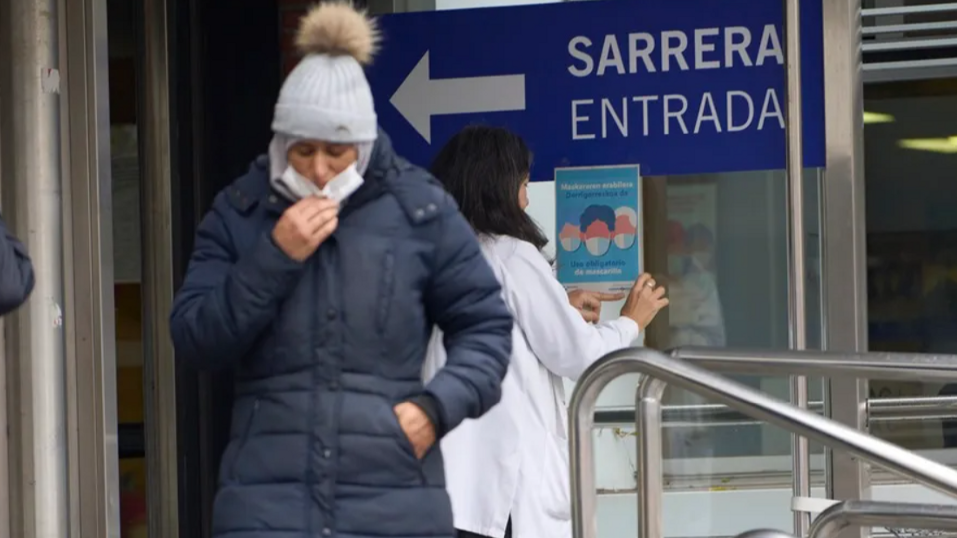 Una trabajadora de un centro de salud de Vitoria coloca un cartel que indica la obligatoriedad del uso de mascarillas.