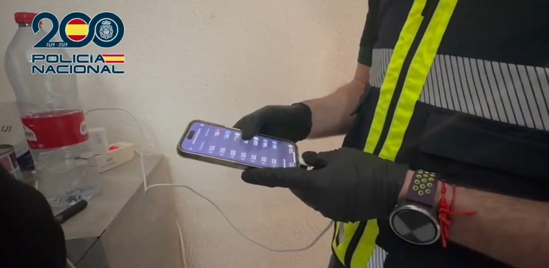 Agente analizando un teléfono móvil incautado a los estafadores