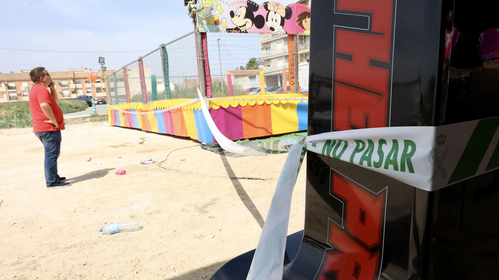 Un hombre observa las camas elásticas del recinto ferial de la pedanía murciana de Alquerías después de que una niña de dos años falleciera