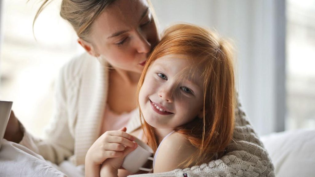 Una madre dándole un beso a su hija