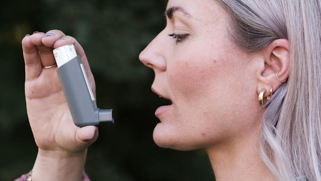 Mujer con asma inhalando "ventolín"