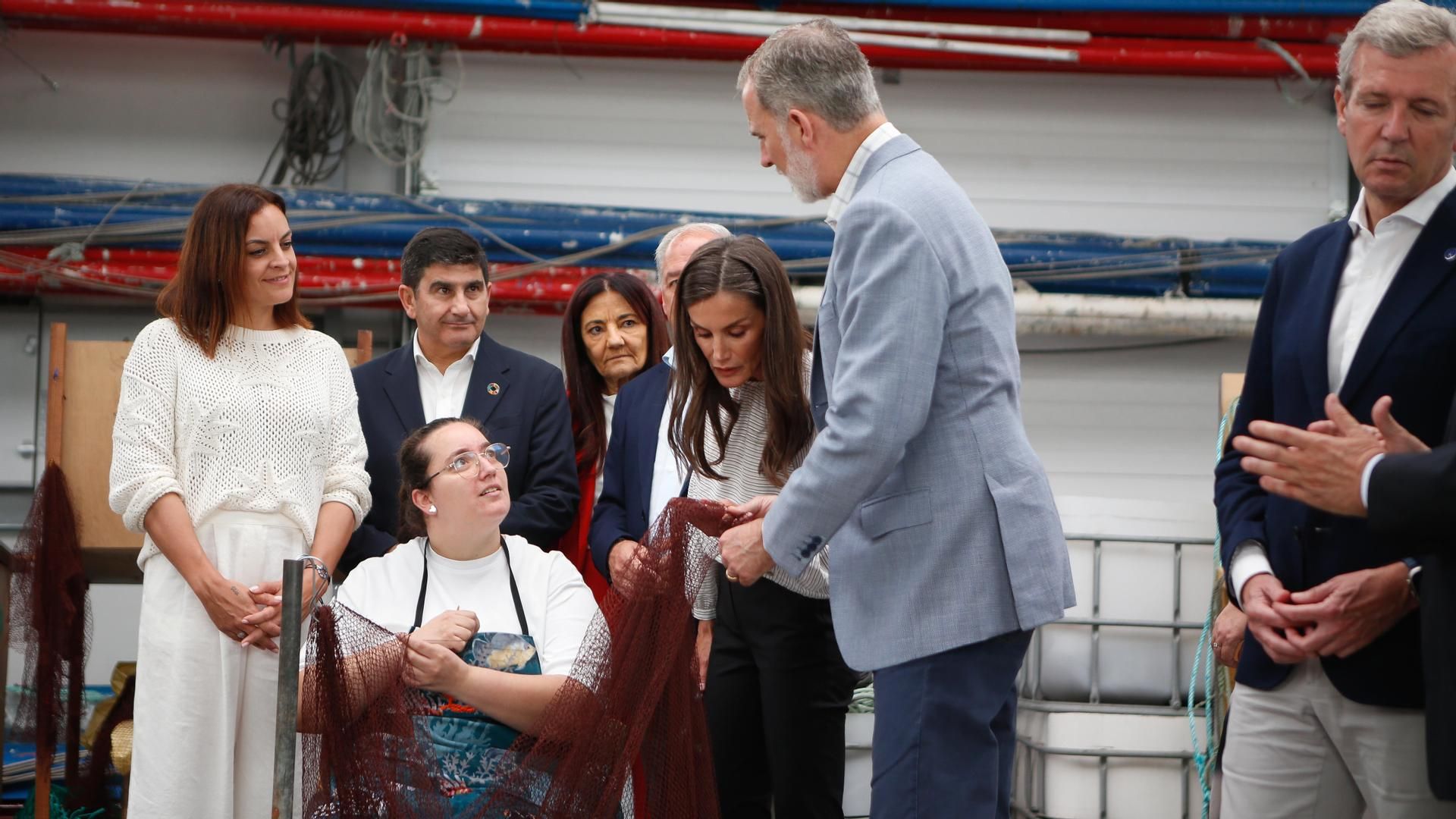 Los reyes Felipe VI y Letizia conversan con una redeira durante una visita a la nave de trabajo Redeiras