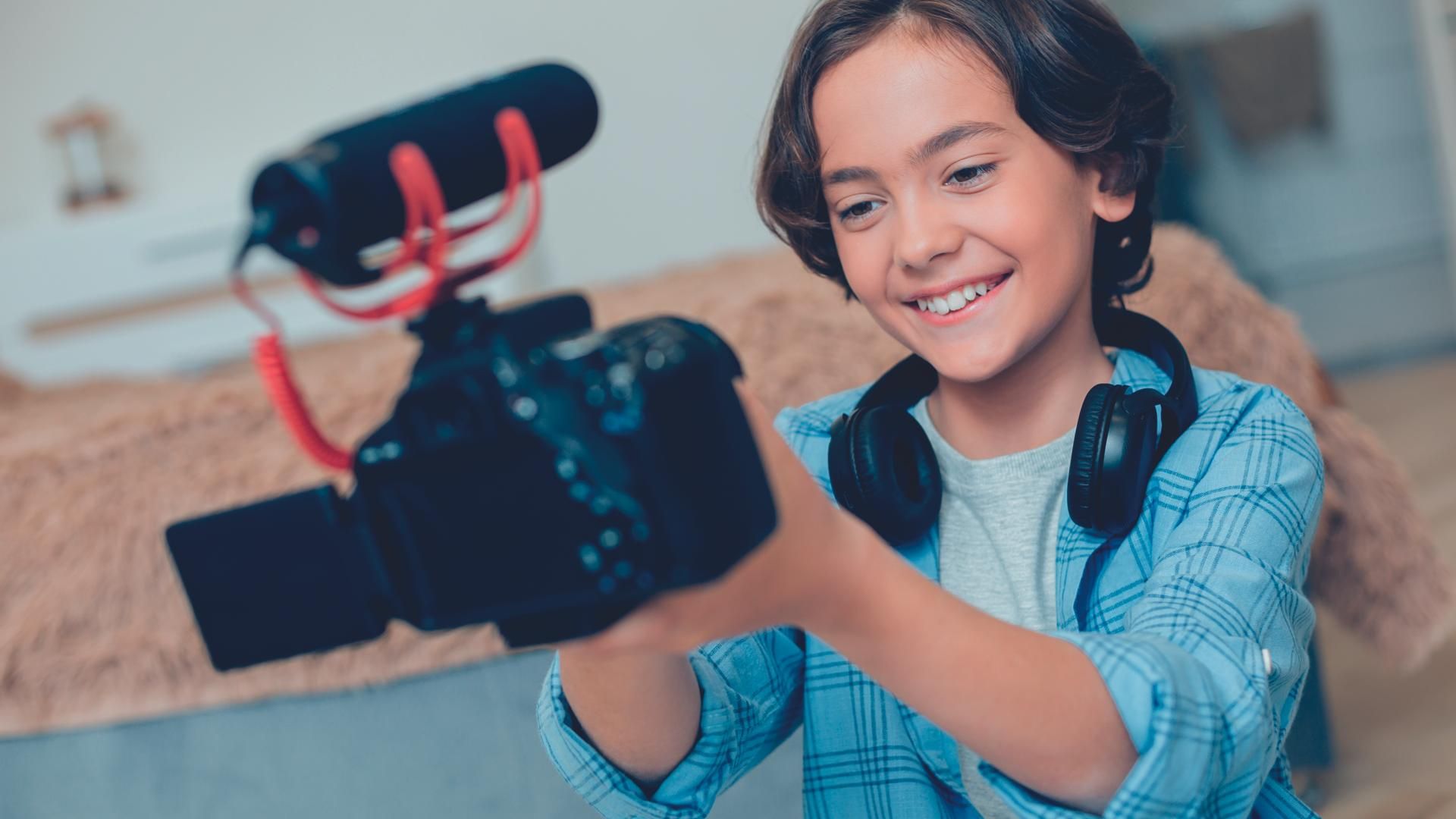 Progressive kid enjoying making videos at home with modern camera