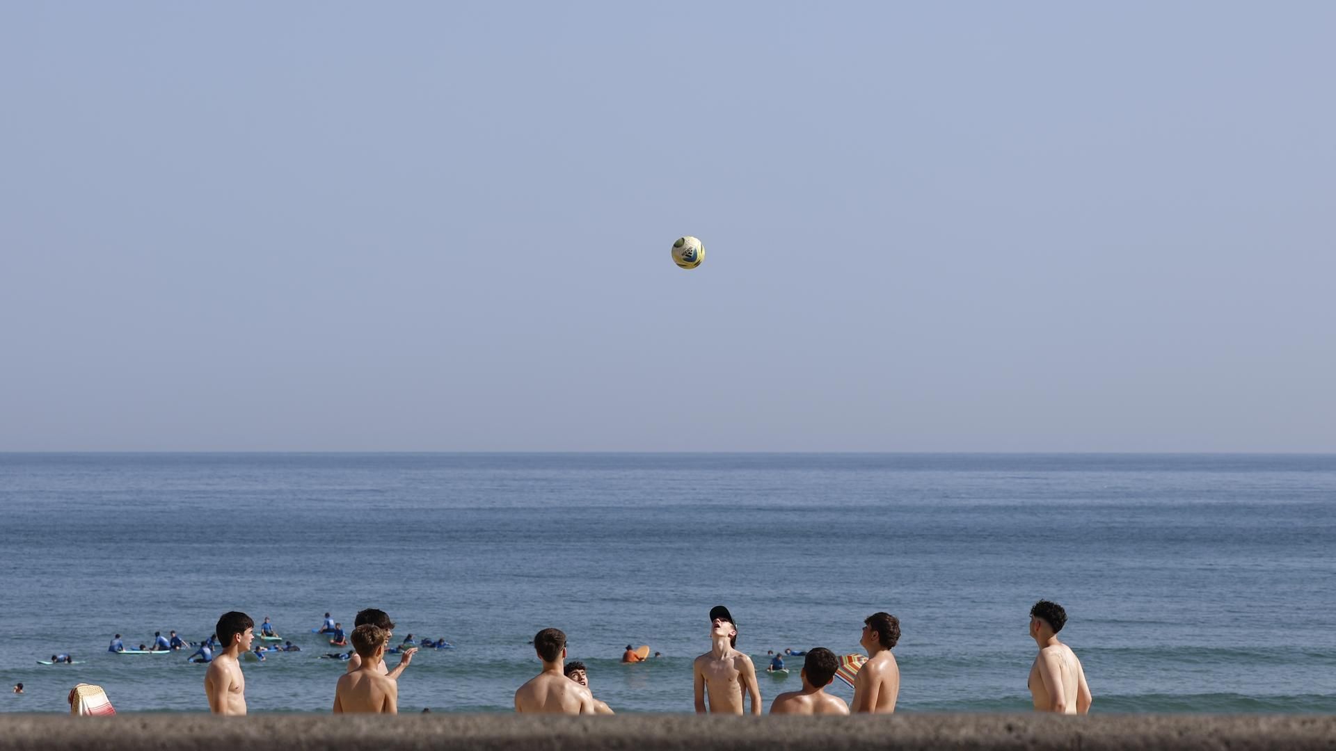 Unos jóvenes juegan con un balón en la playa de la Zurriola de San Sebastián