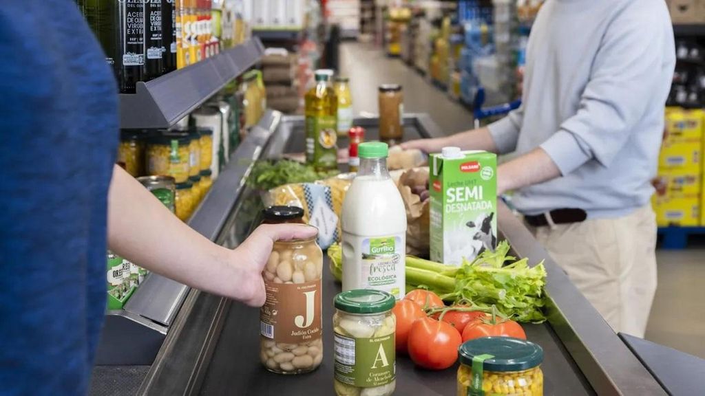 Una cajera cobra los productos a un cliente de un sueprmercado