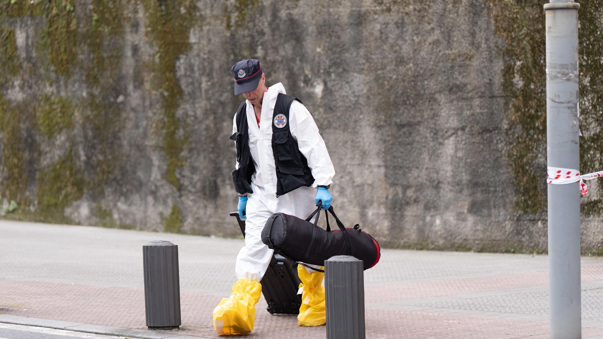 Un agente de policía científica sale de una vivienda tras una investigación.