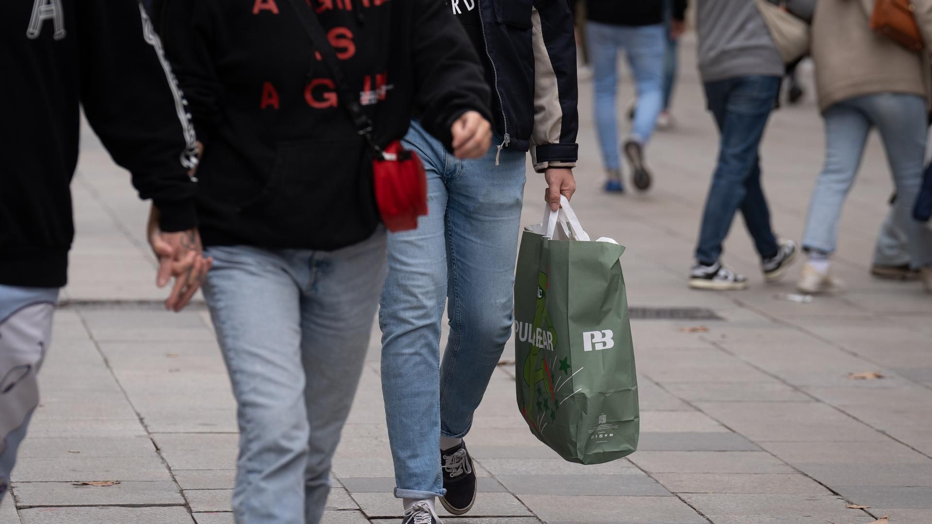 Clientes pasean con bolsas en una calle comercial de Barcelona
