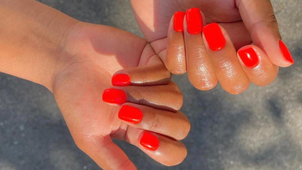 Una chica con uñas naranjas