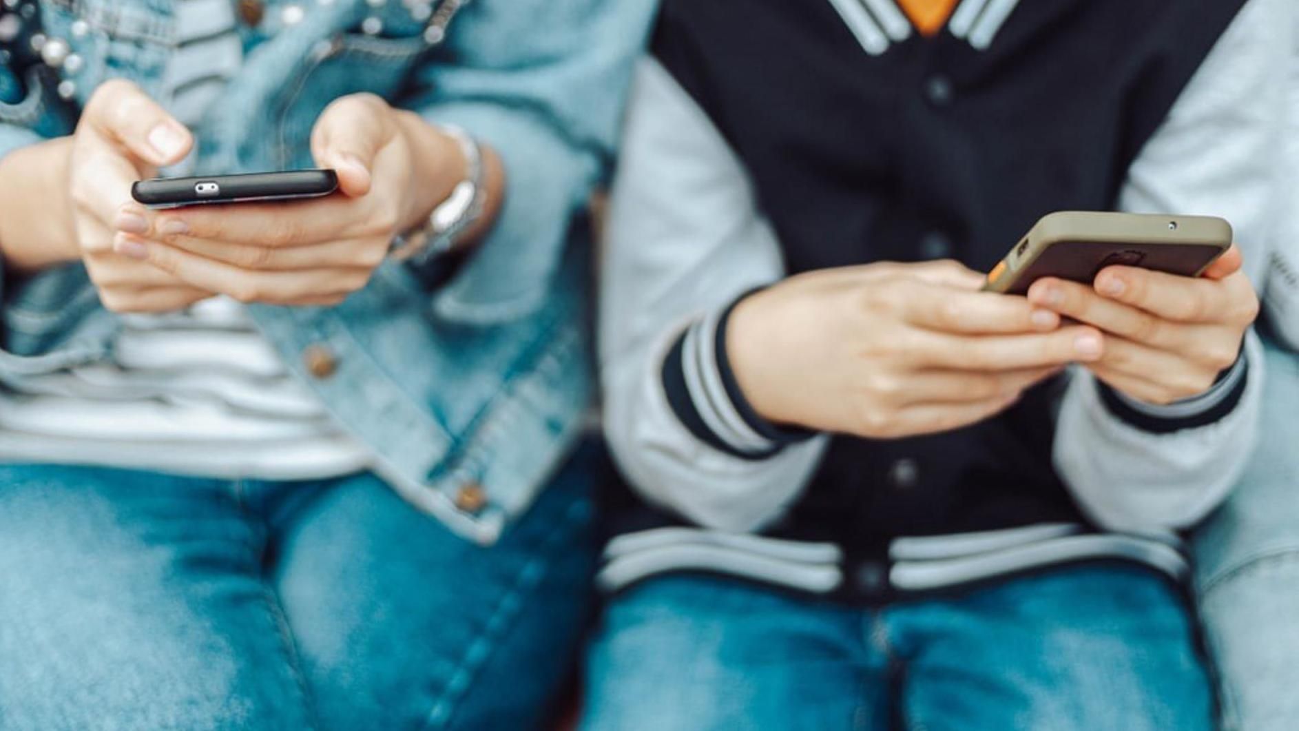 Archivo - Menores de edad miran sus teléfonos móviles.