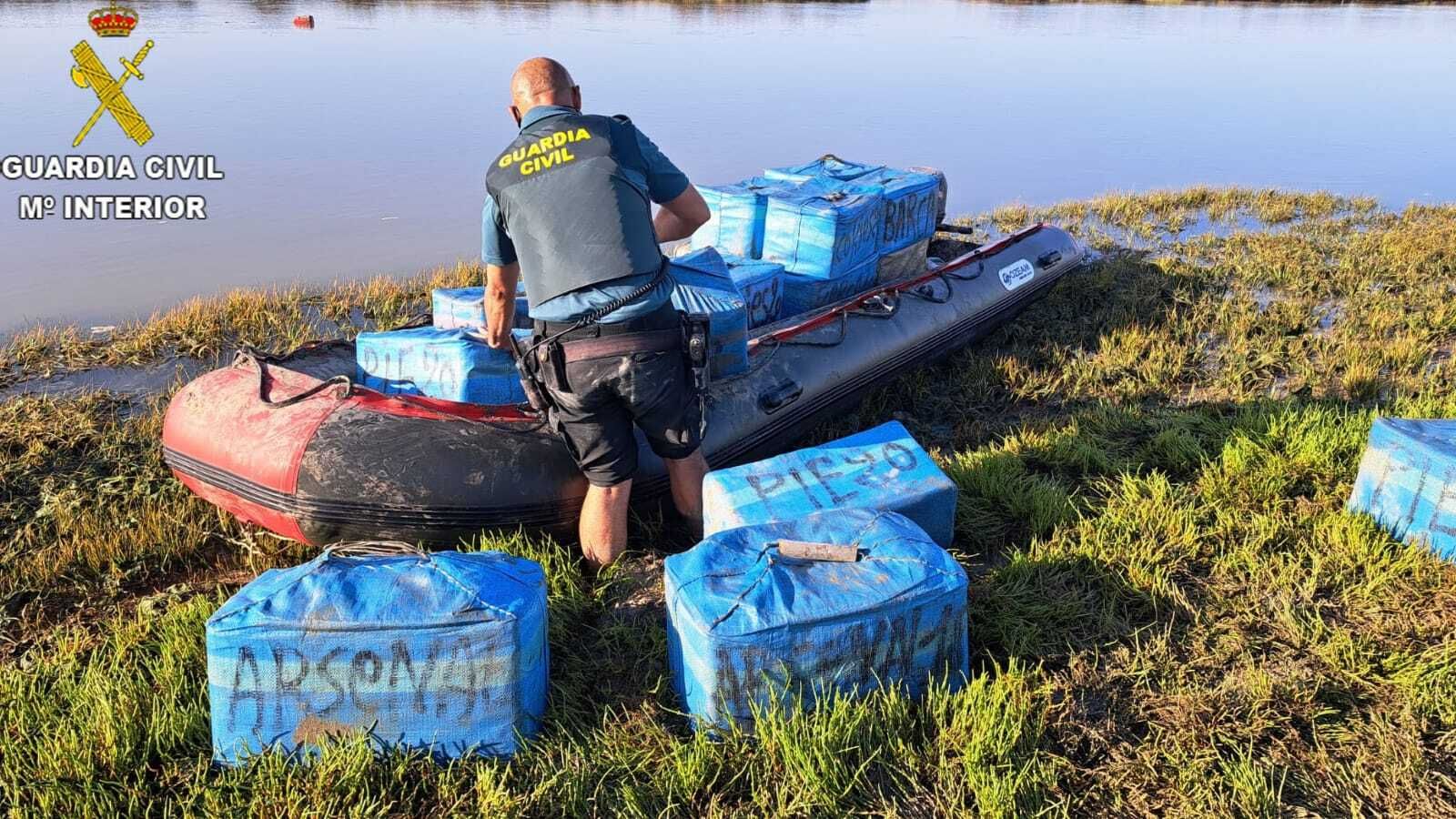 Un agente de la Guardia Civil con algunos de los fardos interceptados.