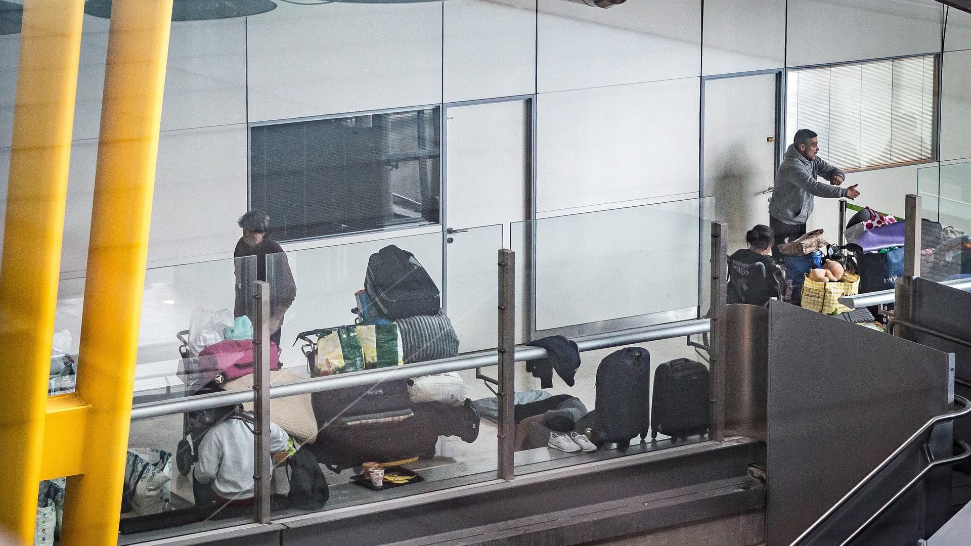 Archivo - Varias personas se preparan para pernoctar en la T4 del Aeropuerto Adolfo Suárez-Madrid Barajas