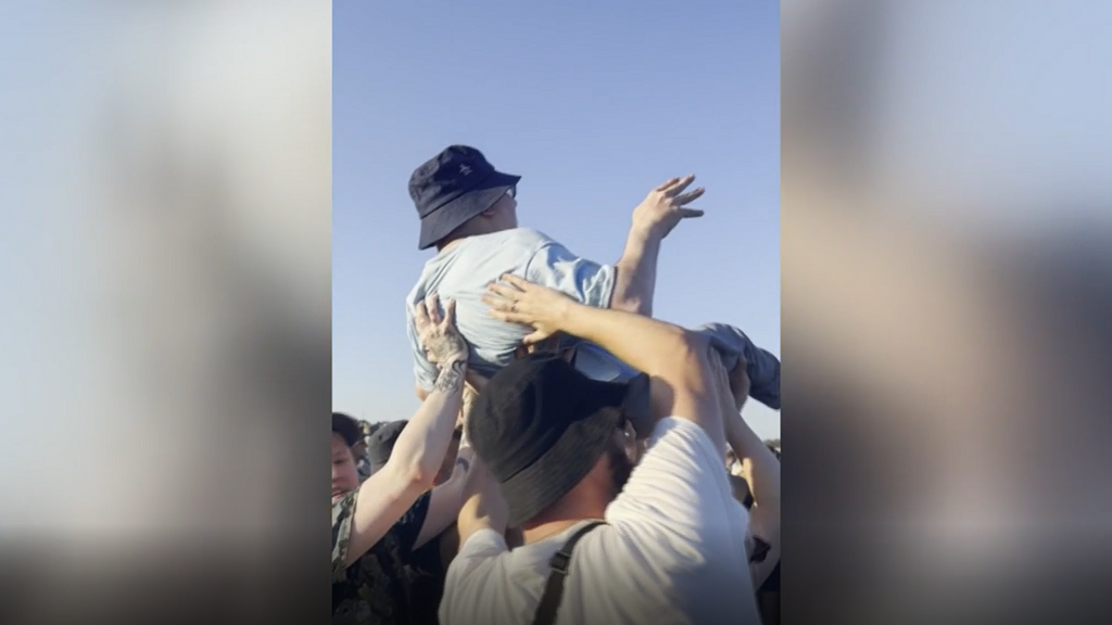Momento en el que levantan a su amigo para que pueda ver el concierto