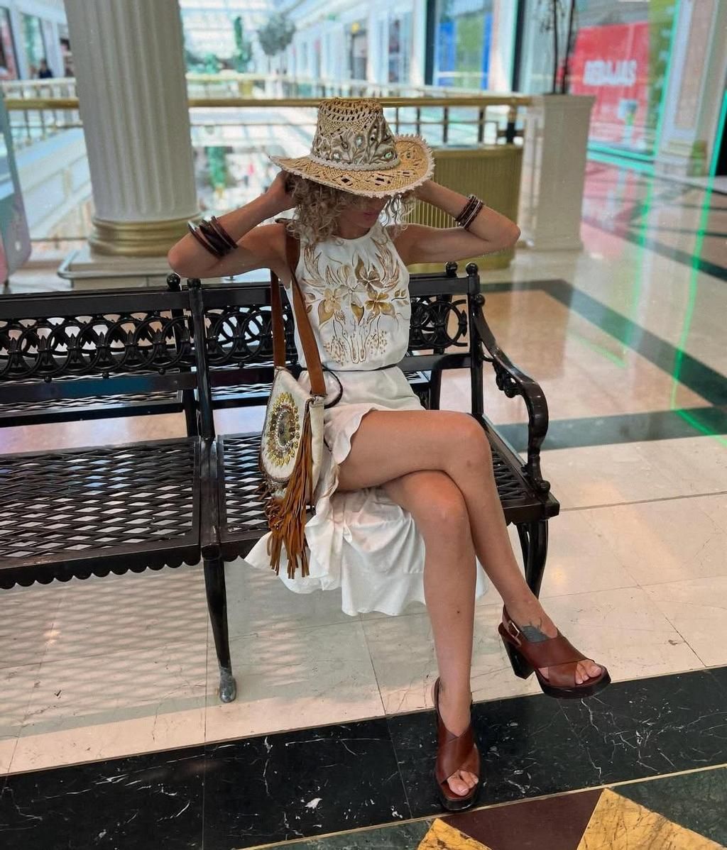 Sheila aparece sentada en un banco, tocándose el pelo