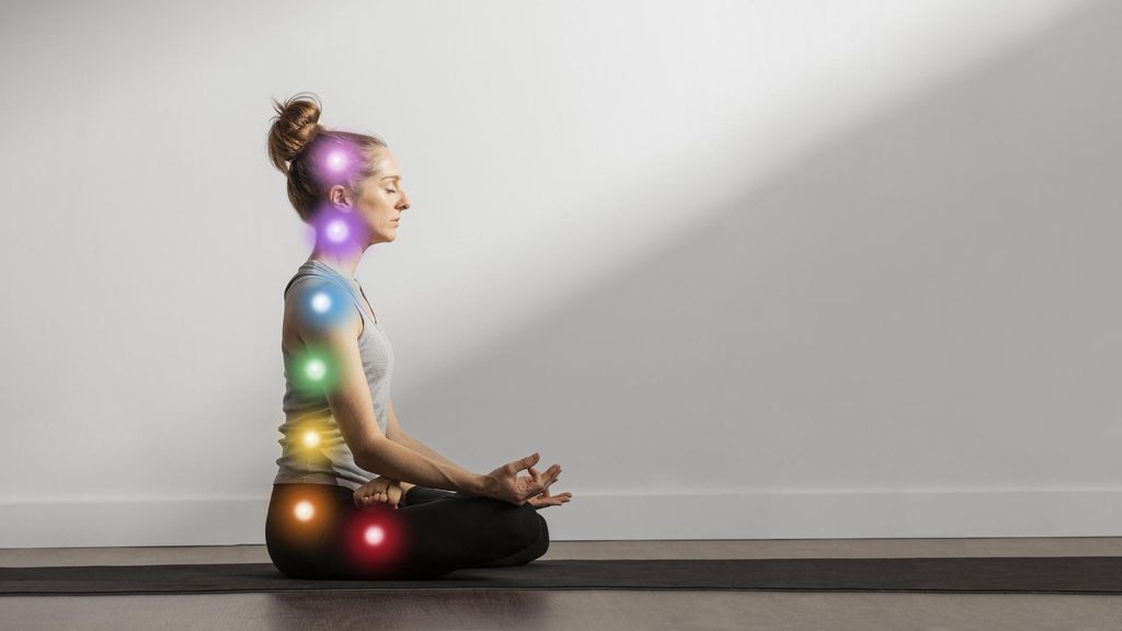 mujer manteniendo asana mientras los puntos de los chakras estan alineados