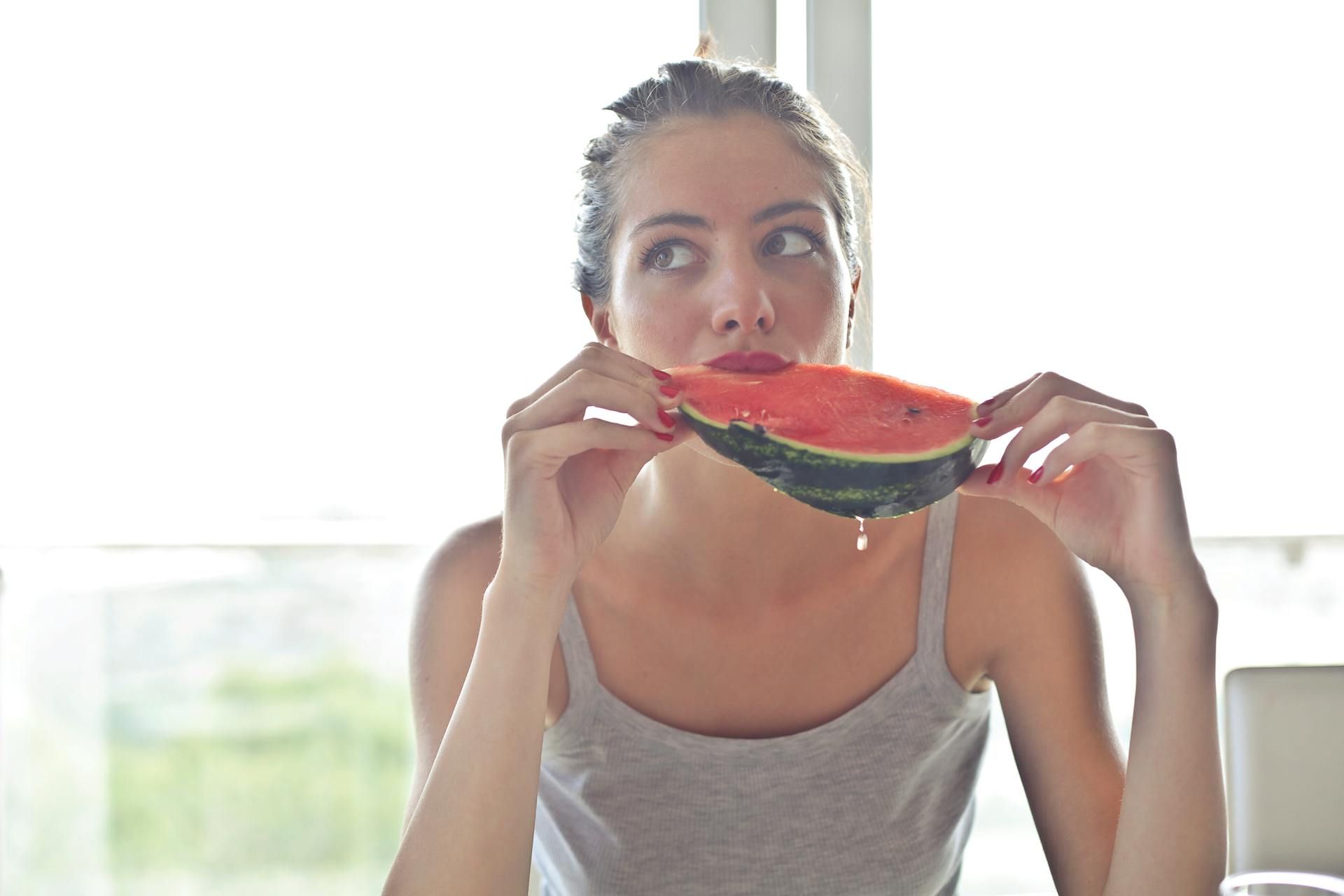 Una mujer come sandía, uno de los alimentos que ayudan a mantenerse hidratada