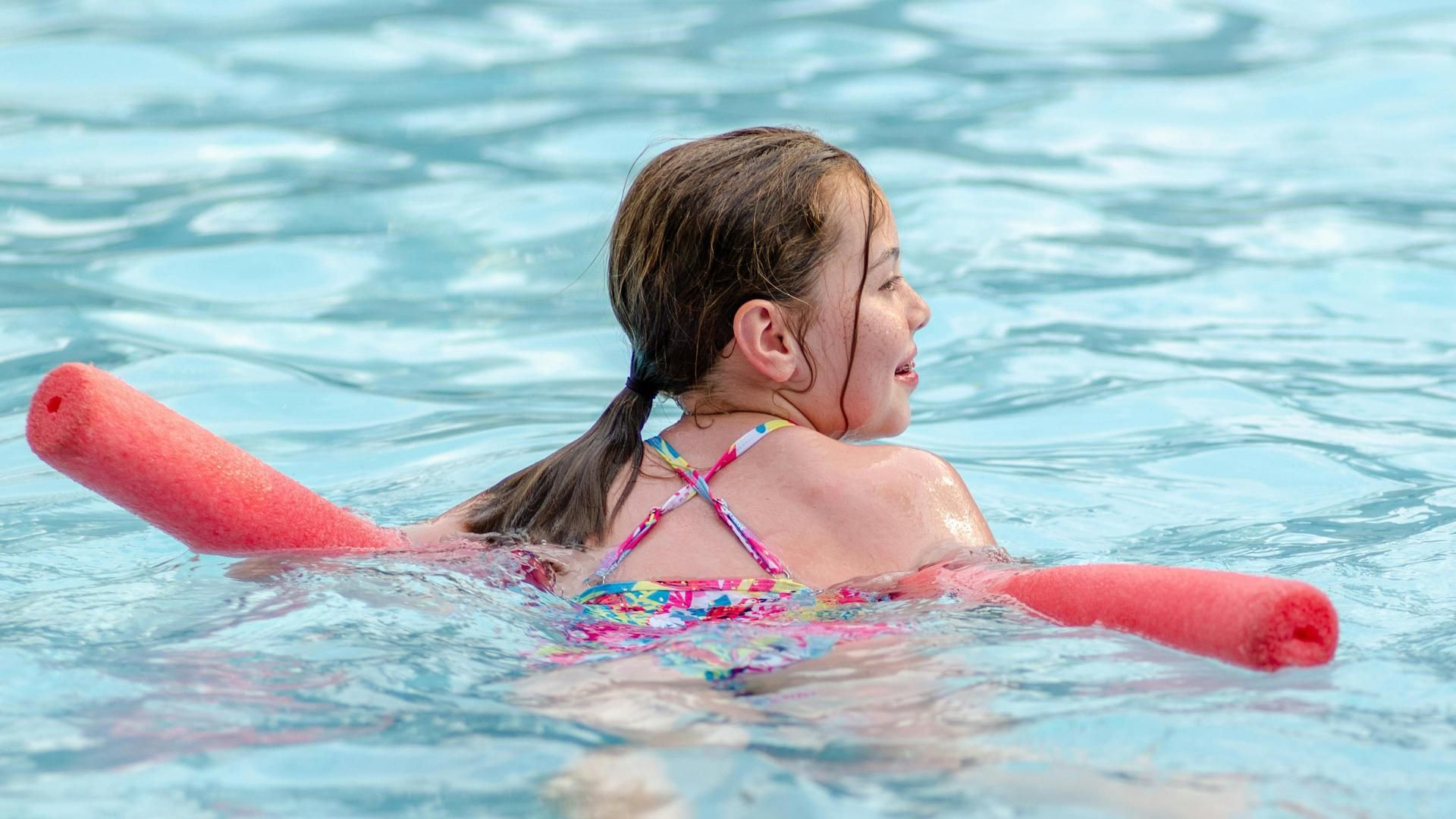 Una niña juega en el agua durante un baño en la piscina