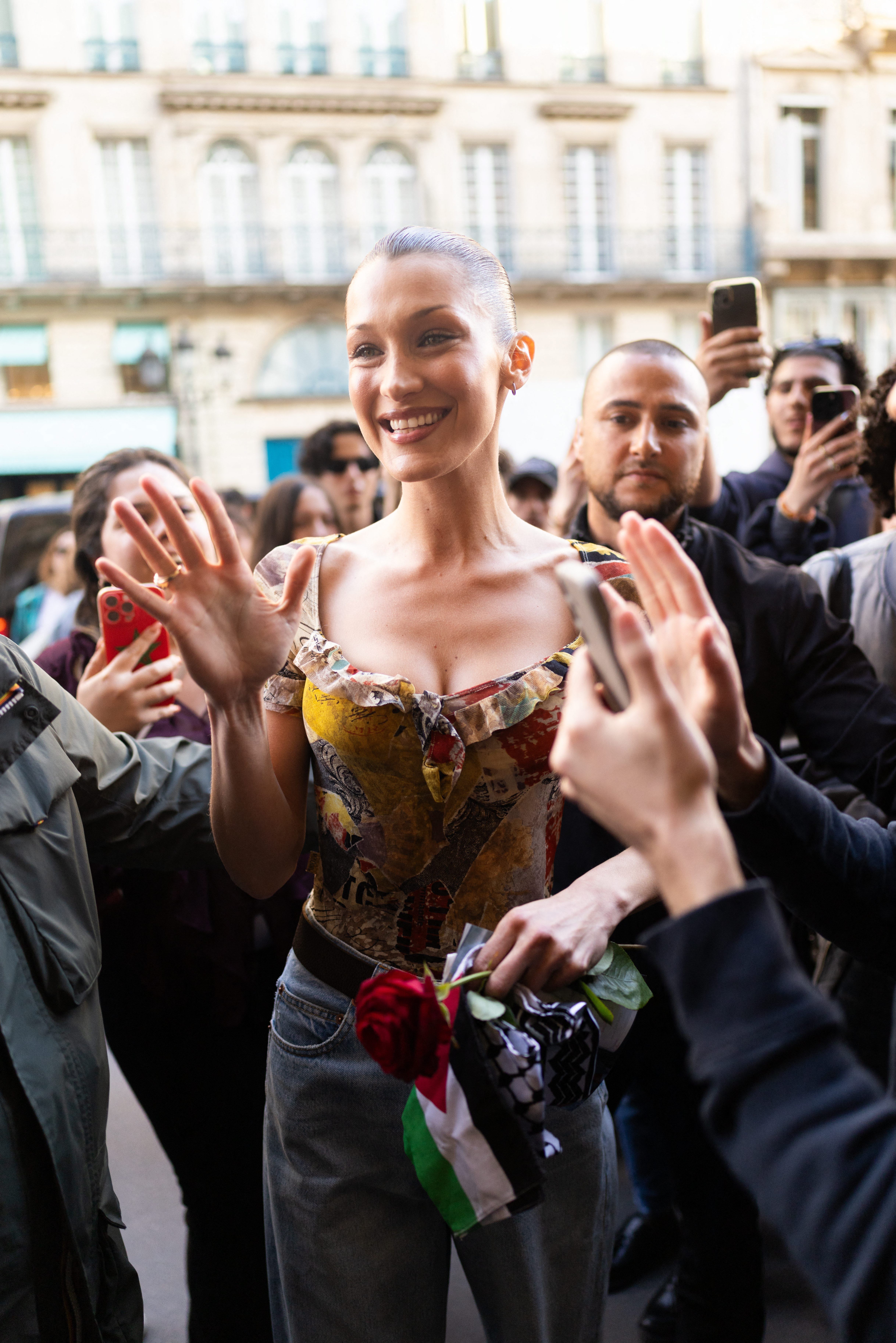 Bella Hadid salundando a sus fans mientras sostiene una bandera de Palestina