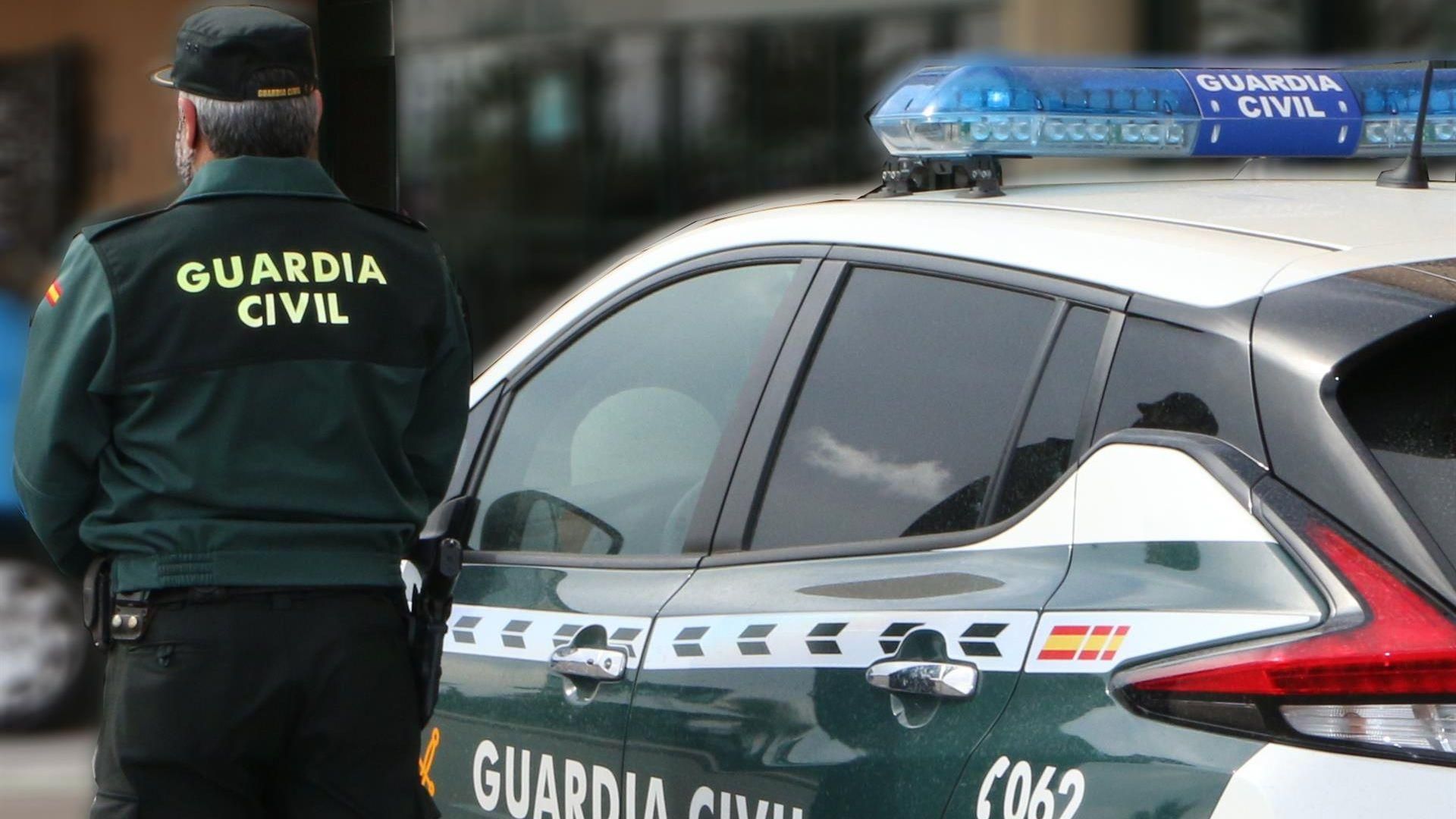 Un agente de la Guardia Civil, de espaldas, de pie junto a un vehículo oficial Un agente de la Guardia Civil, de espaldas, de pie junto a un vehículo oficial