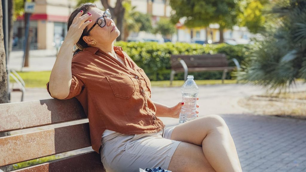 Una mujer bebiendo agua en un banco