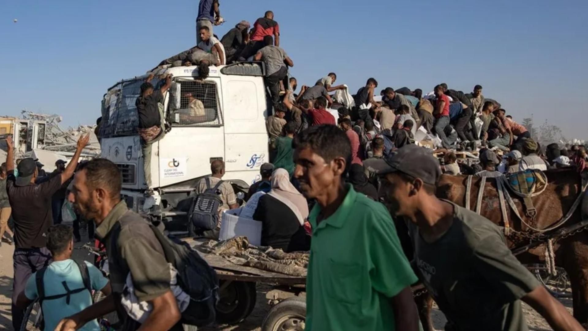 Grupos de palestinos suben a camiones de ayuda para conseguir alimentos en el corredor de Morag, al sur de la Franja