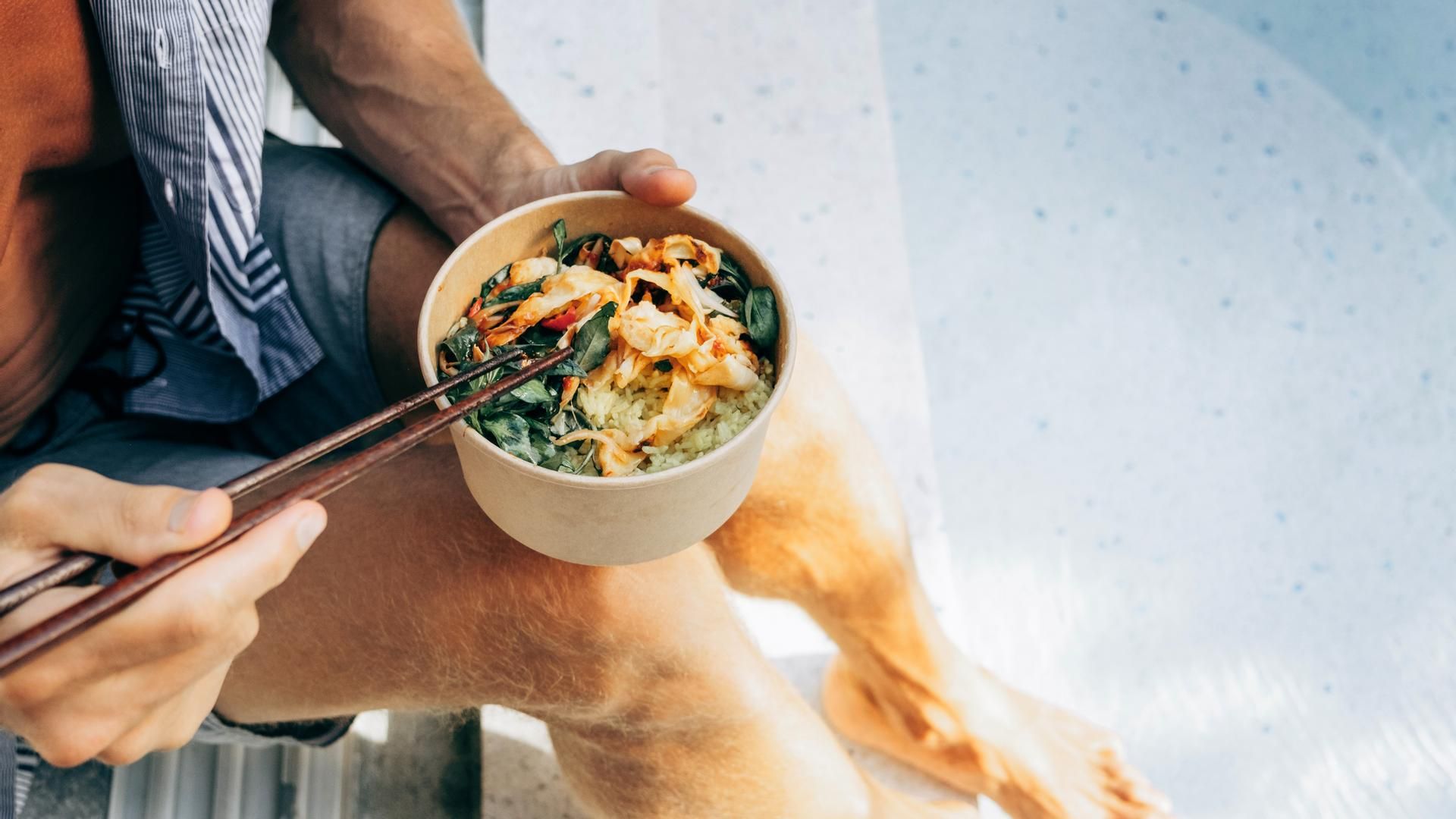 Un hombre come mientras está en la piscina