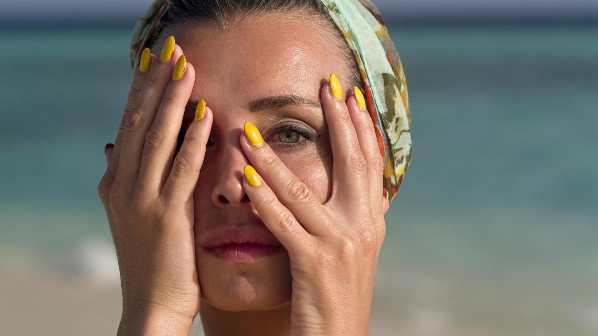 Una muejr con uñas amarillas en la playa