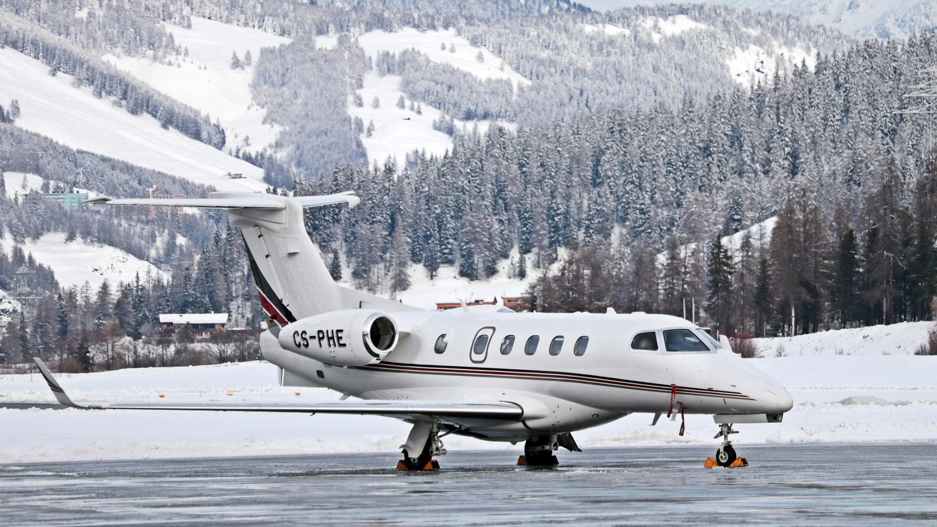 Un jet privado espera sobre una pista de aterrizaje rodeado de un paisaje nevado