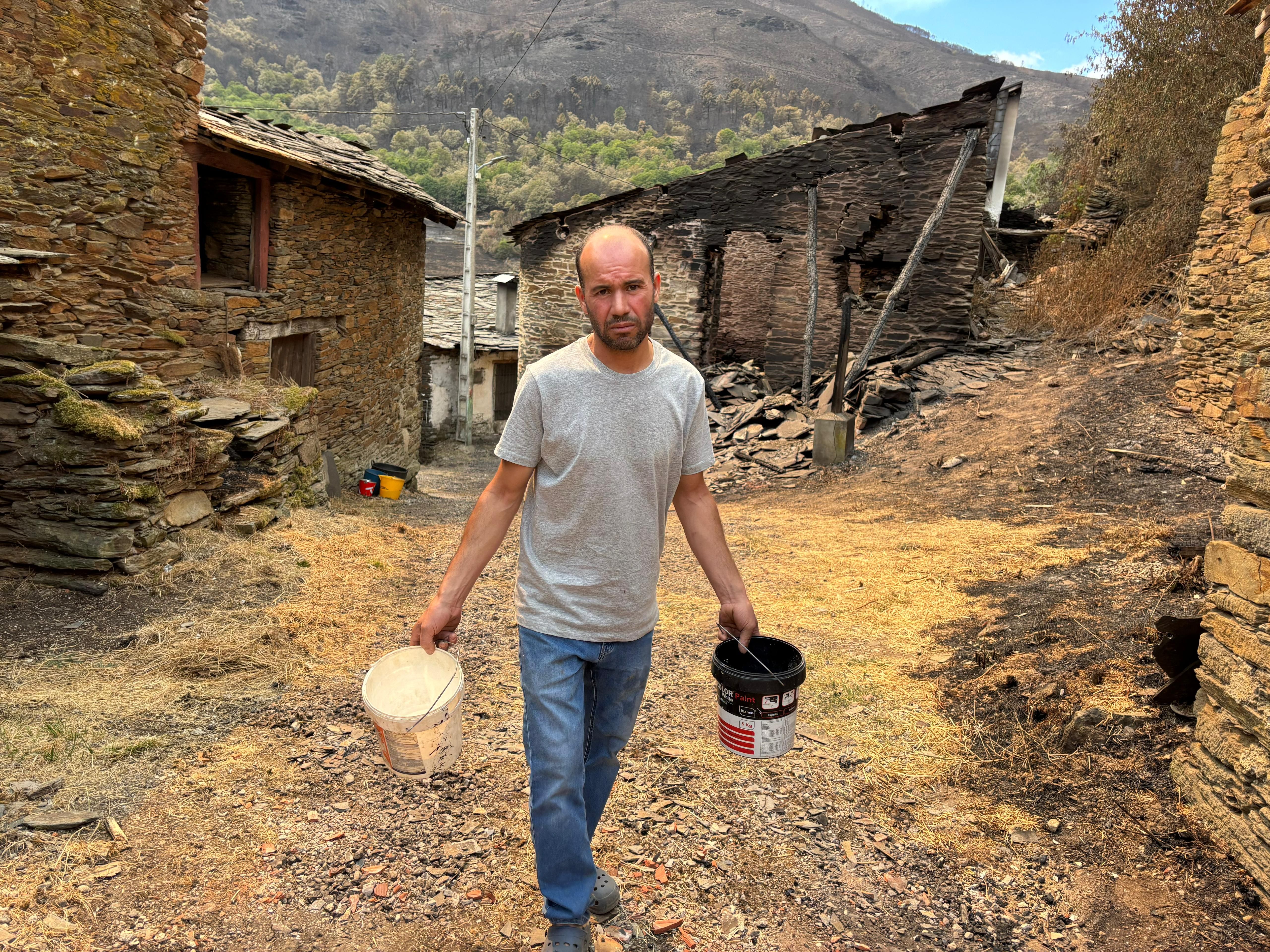 Ahmed, vecino de Cernego enseña los cubos que utilizó para parar el fuego en su aldea