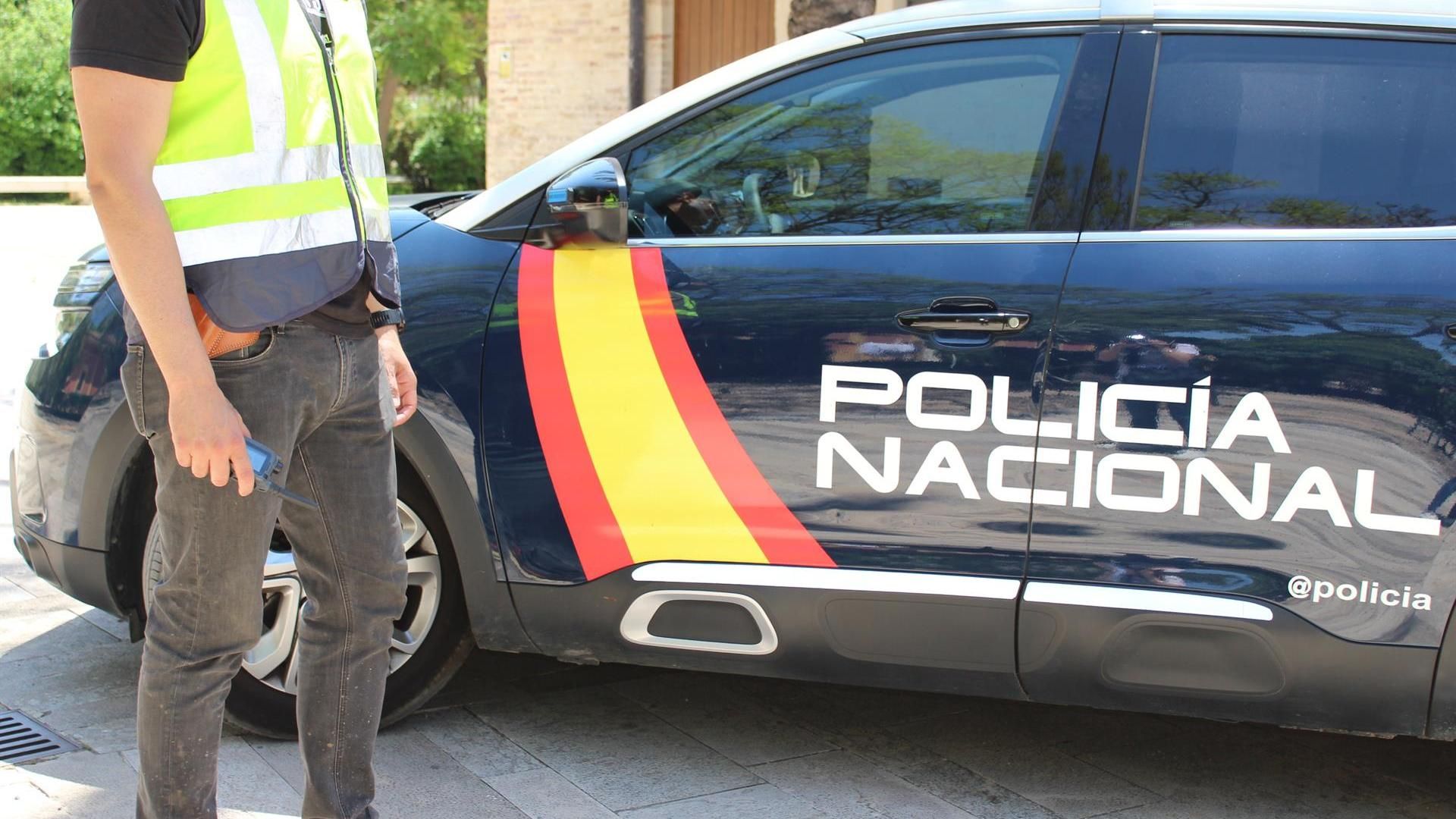 Agente Policía Nacional junto a un vehiculo policial