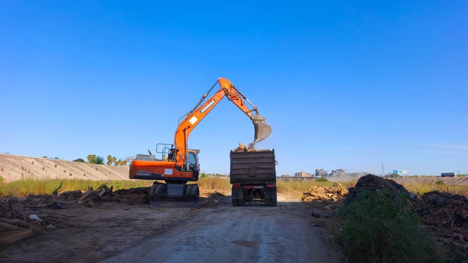Una excavadora retira desechos del cauce del río Turia