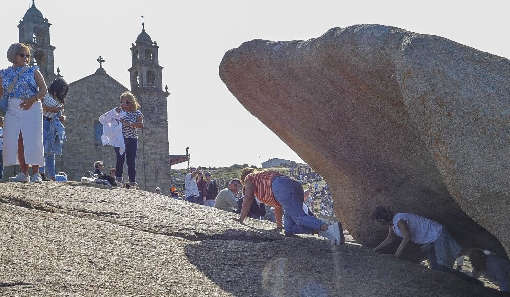 Feligreses pasando por debajo de la "Pedra dos cadrís" en la romería de 2024