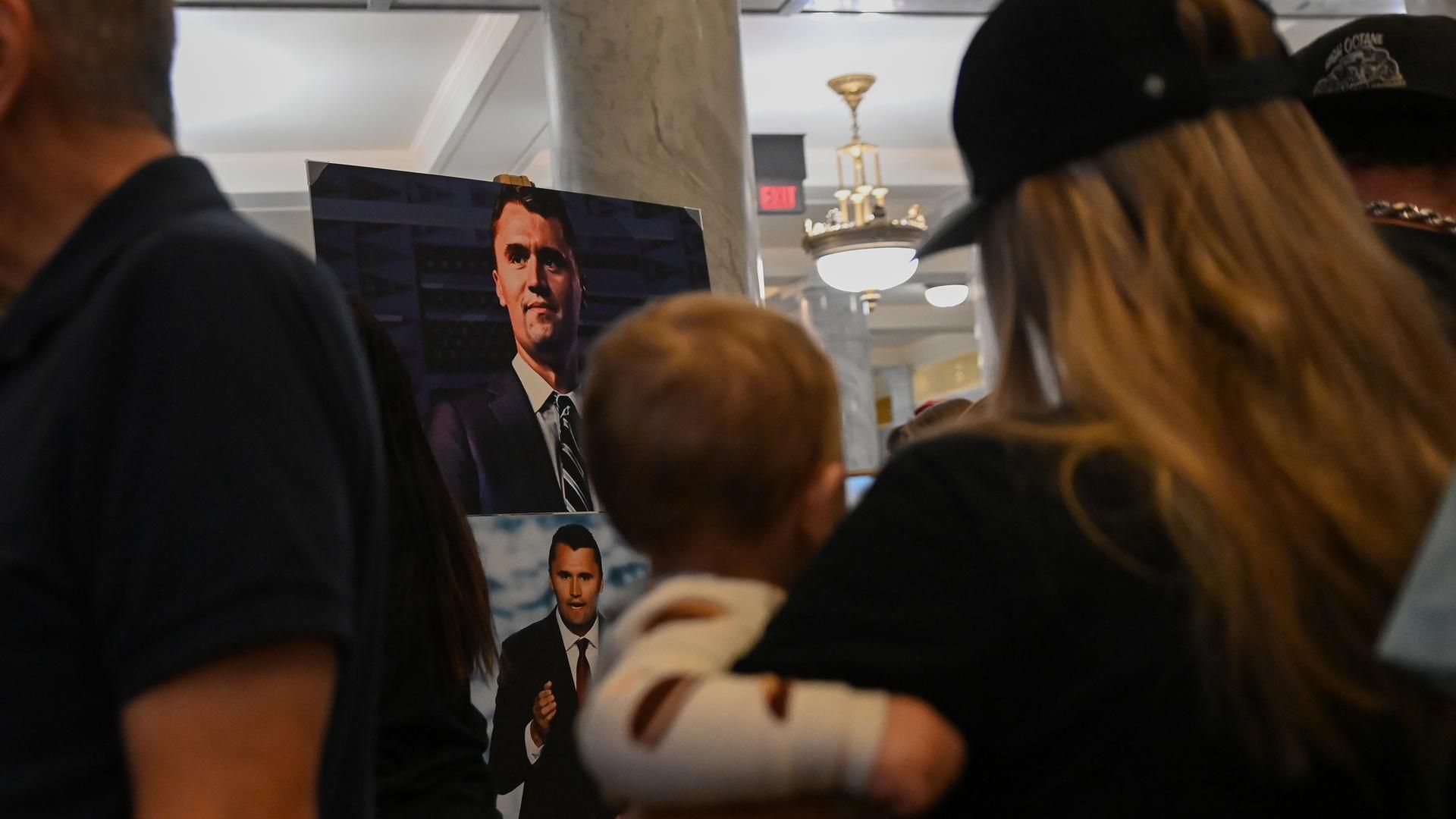 September 10, 2025, Salt Lake City, Utah, USA: A woman and a baby in. her arms, look at a photo of slain Turning Point founder Charlie Kirk, which stands in the Utah State Capitol. Kirk was assassinated during an event at Utah Valley University, in front of a large crowd. (Credit Image: © Madeleine Kelly/ZUMA Press Wire)