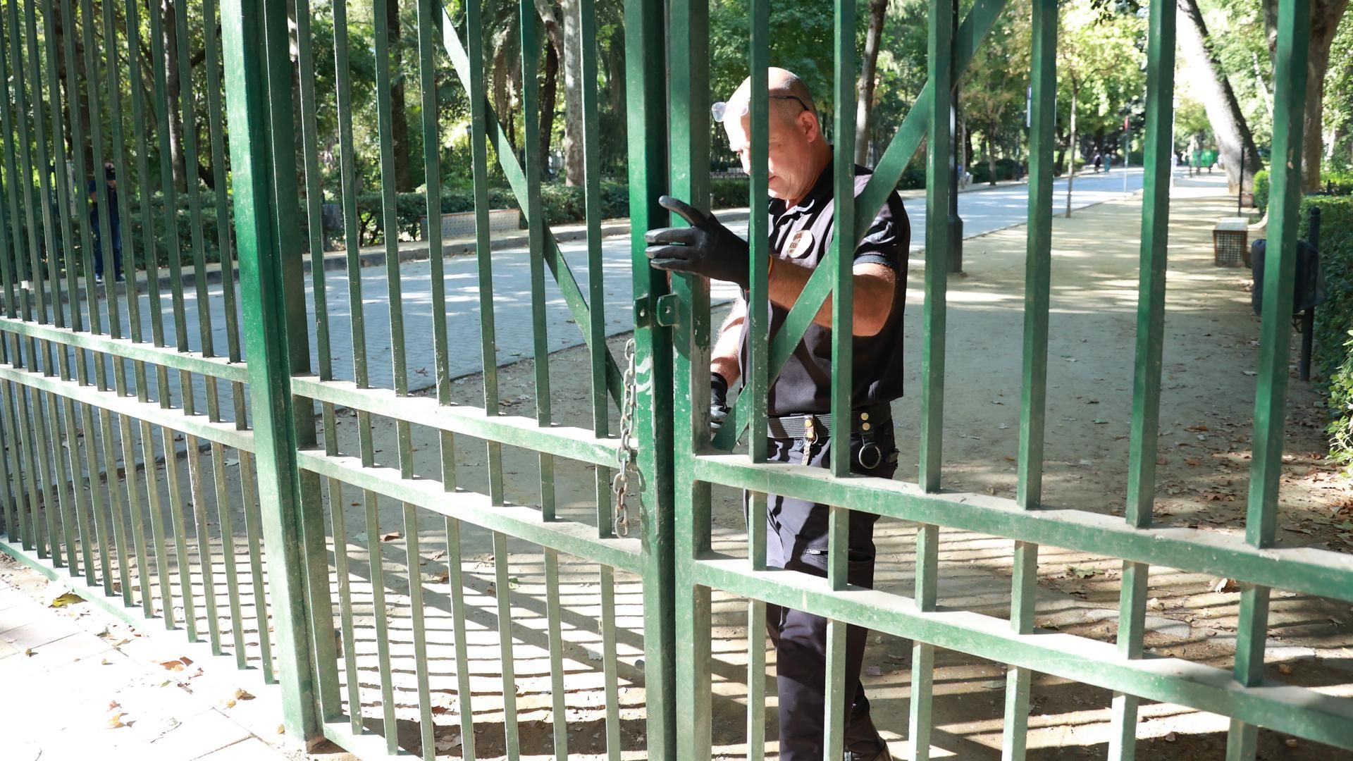 Un empleado de seguridad cierra la puerta de acceso al parque de María Luisa de Sevilla
