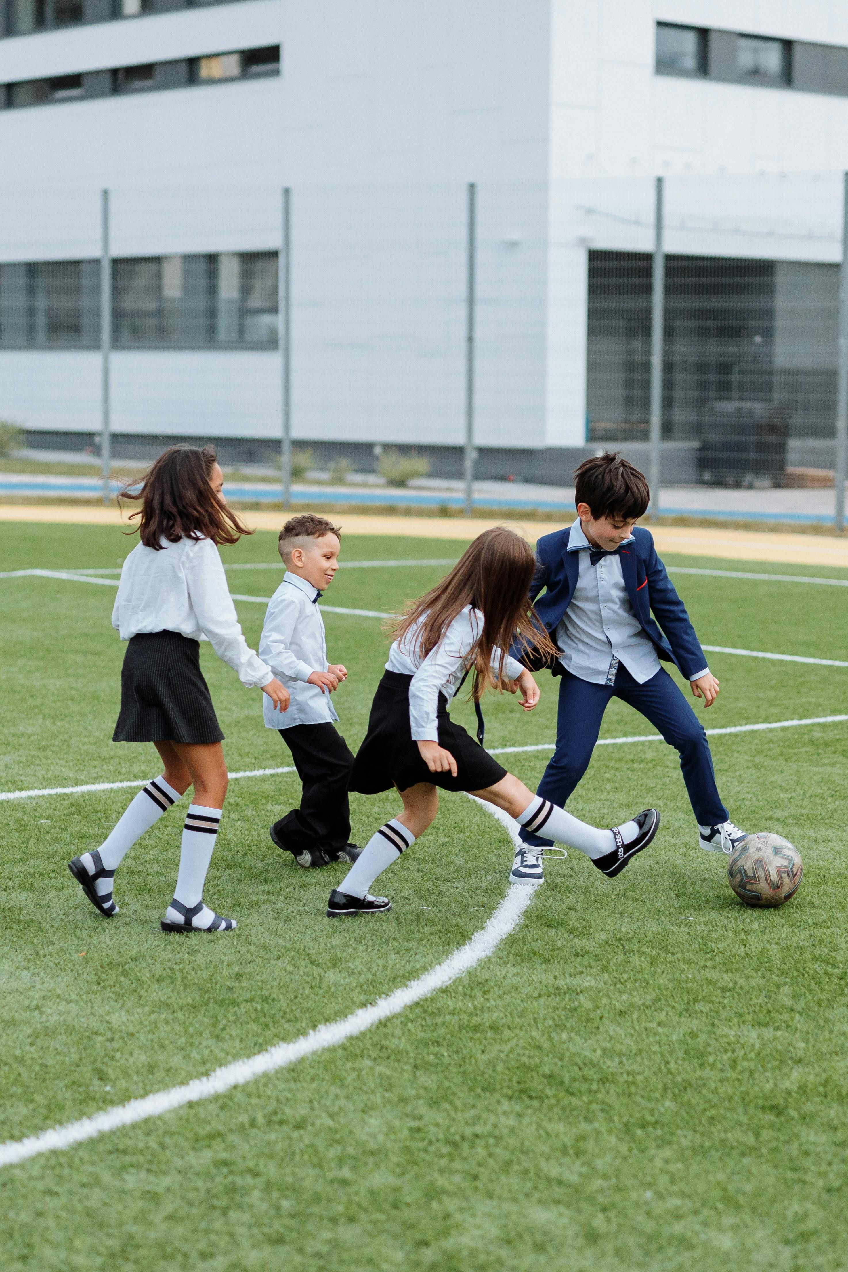 Niños de uniforme jugando al balón