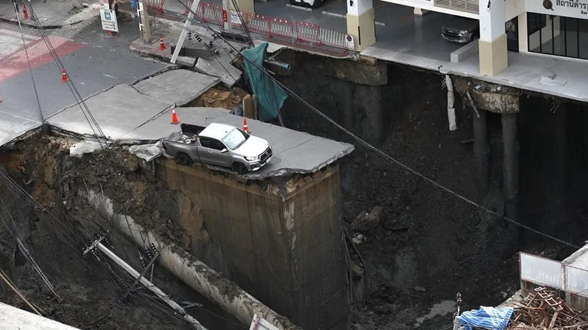 Un vehículo atrapado en un gran socavón tras un derrumbe en Bangkok.