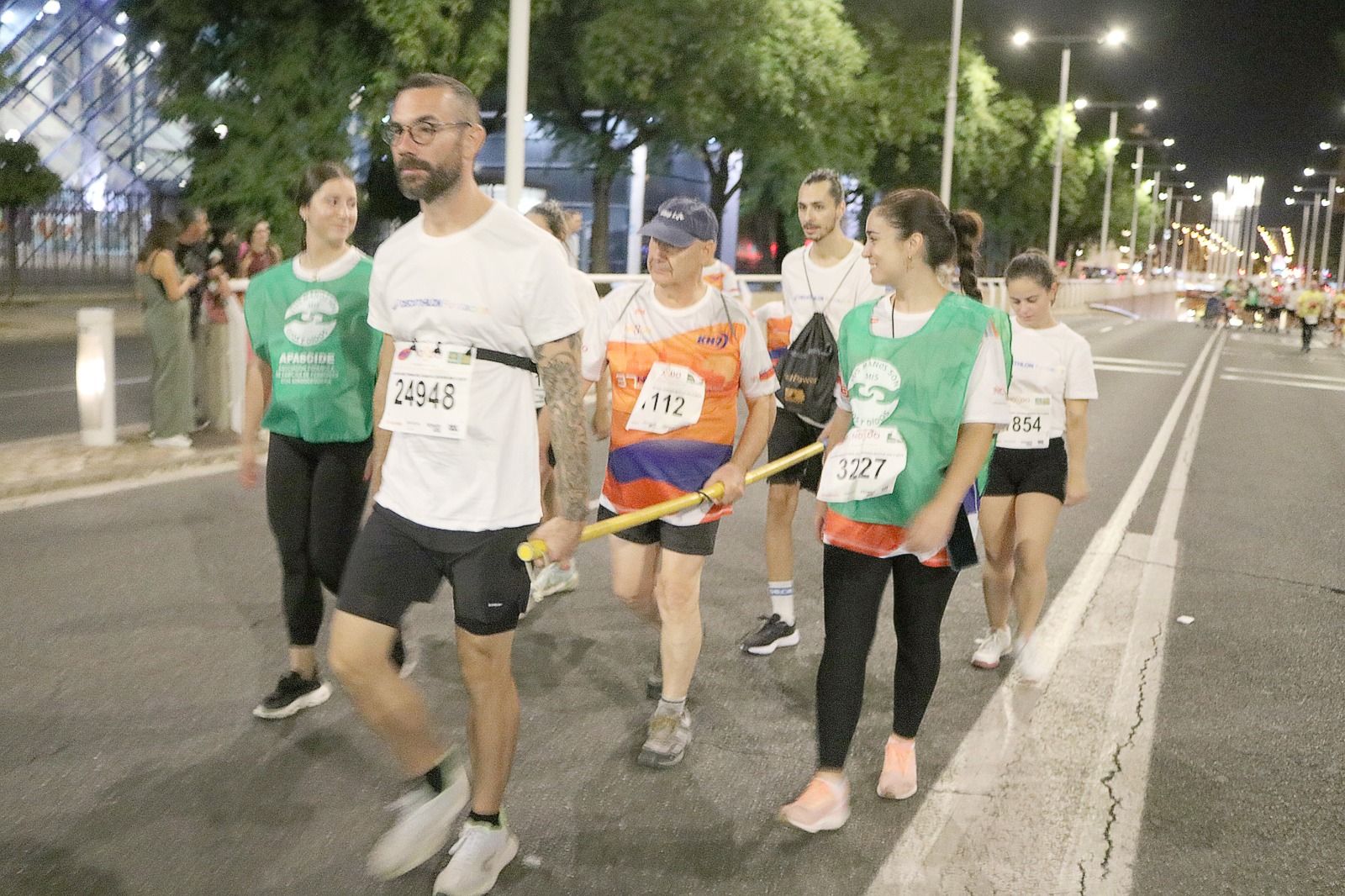 Una persona con sordoceguera, el segundo agarrado a la barra, corriendo en la Carrera Nocturna del Guadalquivir