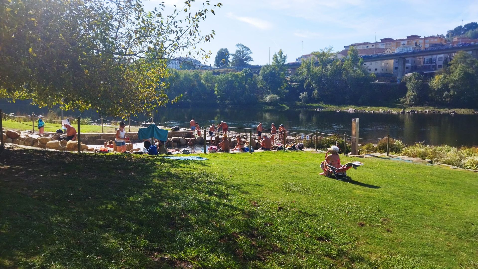 Un día más propio de verano en Ourense anima a los vecinos a tomar el sol y bañarse en el río