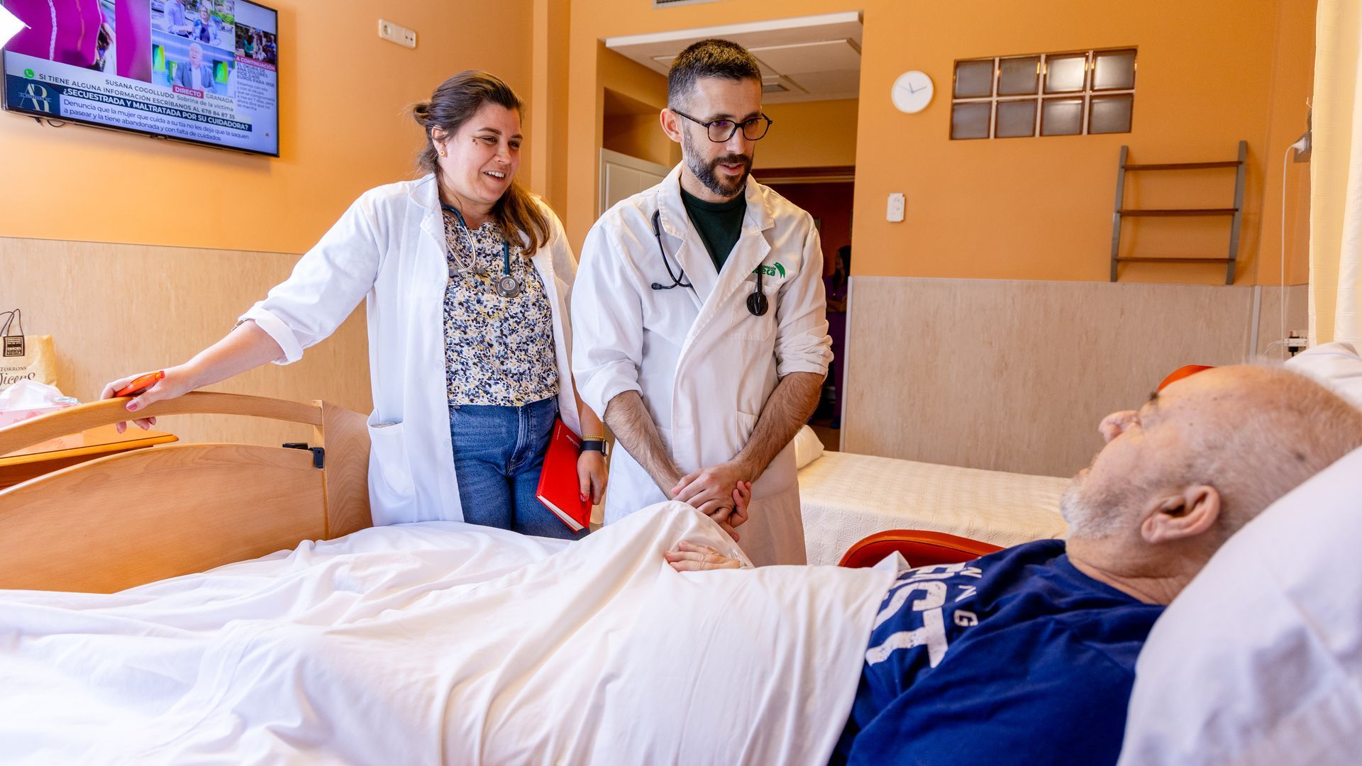 Dos trabajadores de Cudeca atienden a uno de sus pacientes