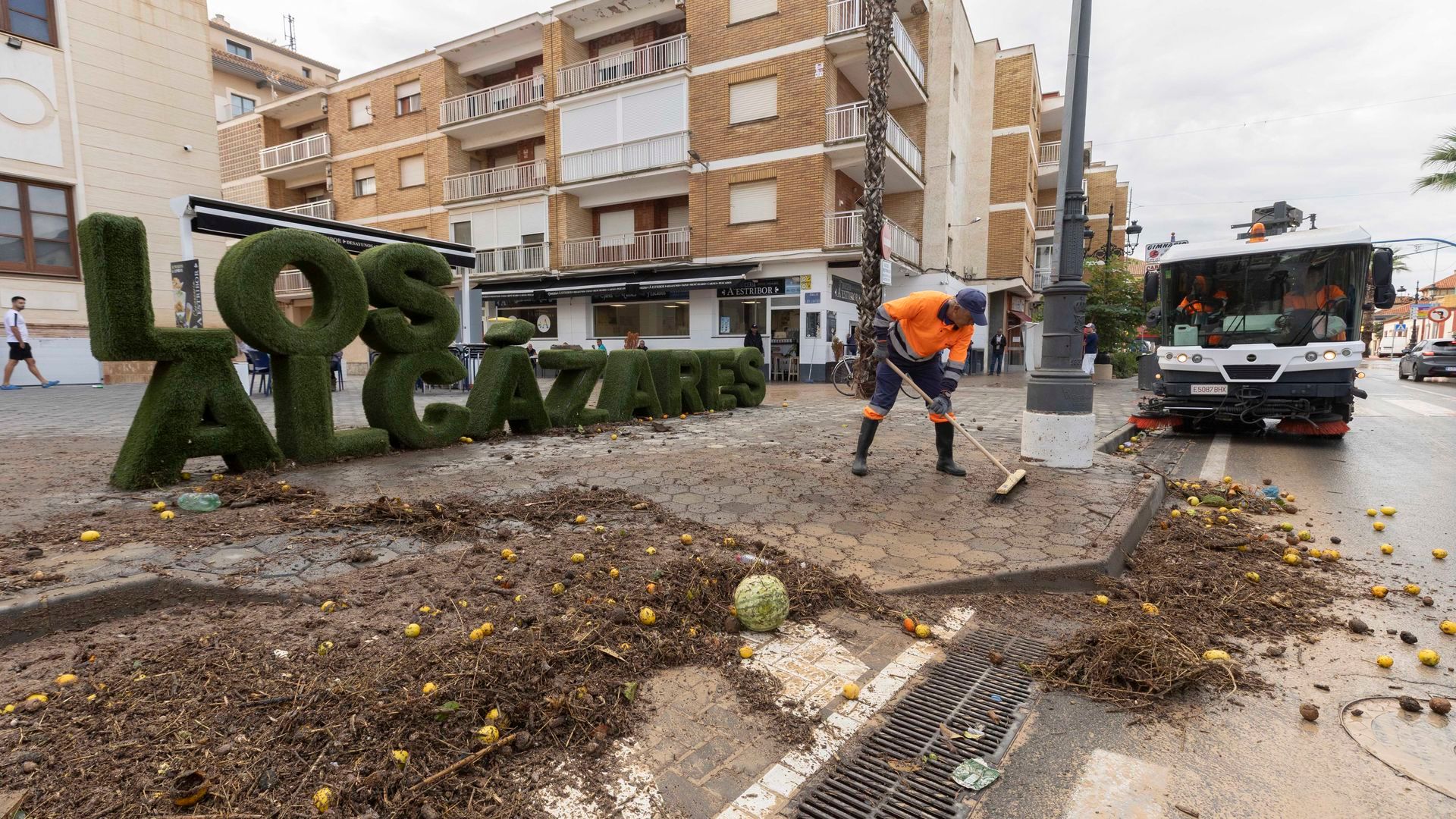 Personal del Ayuntamiento de Los Alcázares (Murcia) despeja un acera cubierta de vegetación tras la lluvia
