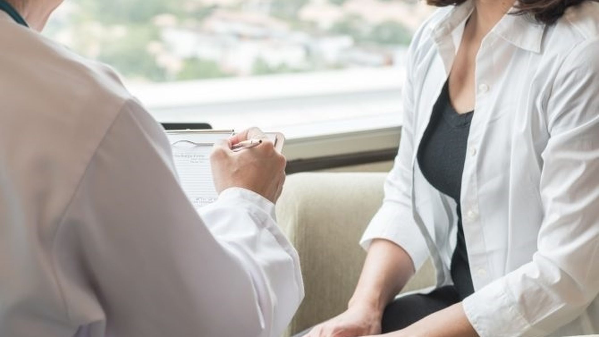 Un facultativo atiende a una mujer en su consulta