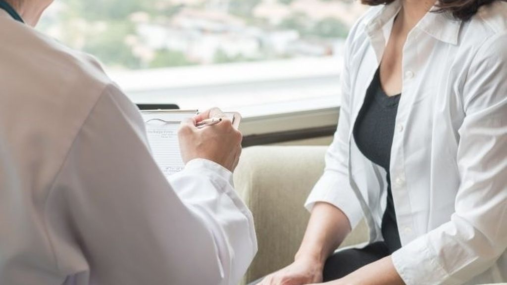 Un facultativo atiende a una mujer en su consulta