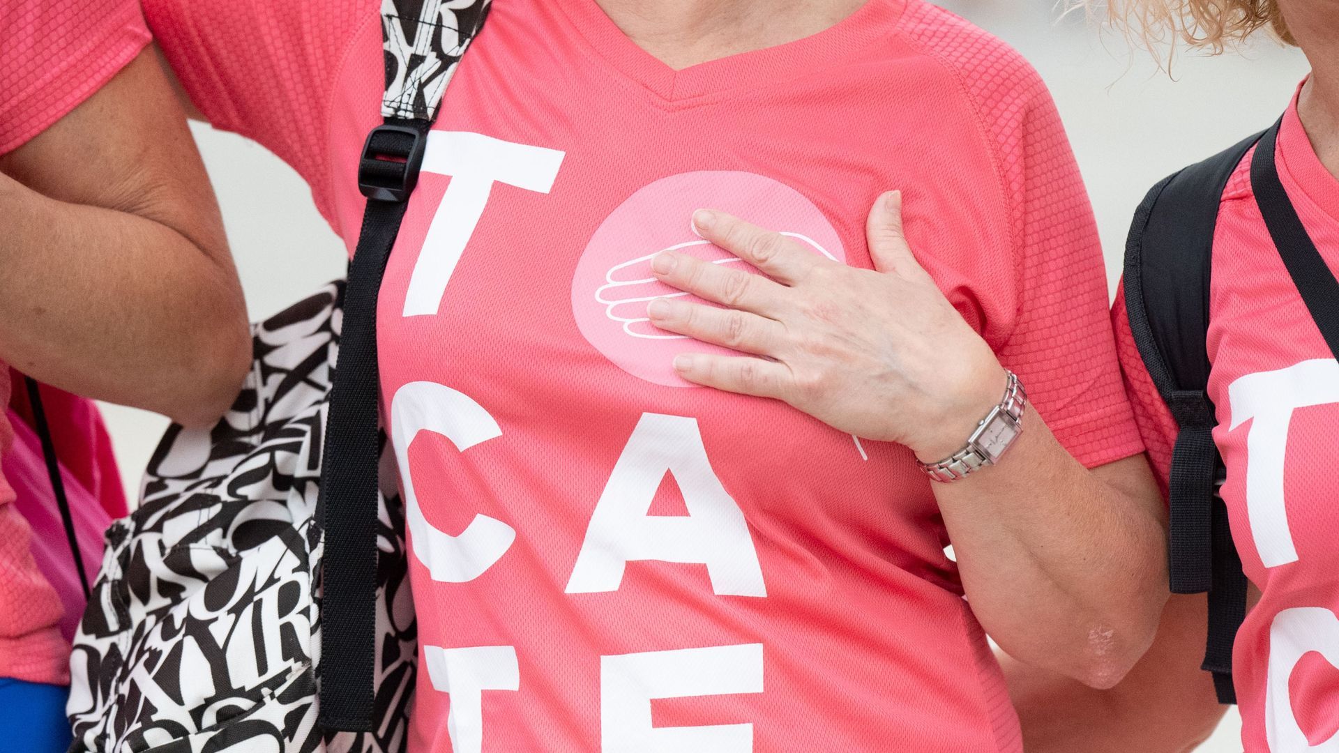 Muejeres se tocan el pecho en una marcha por el cáncer de mama