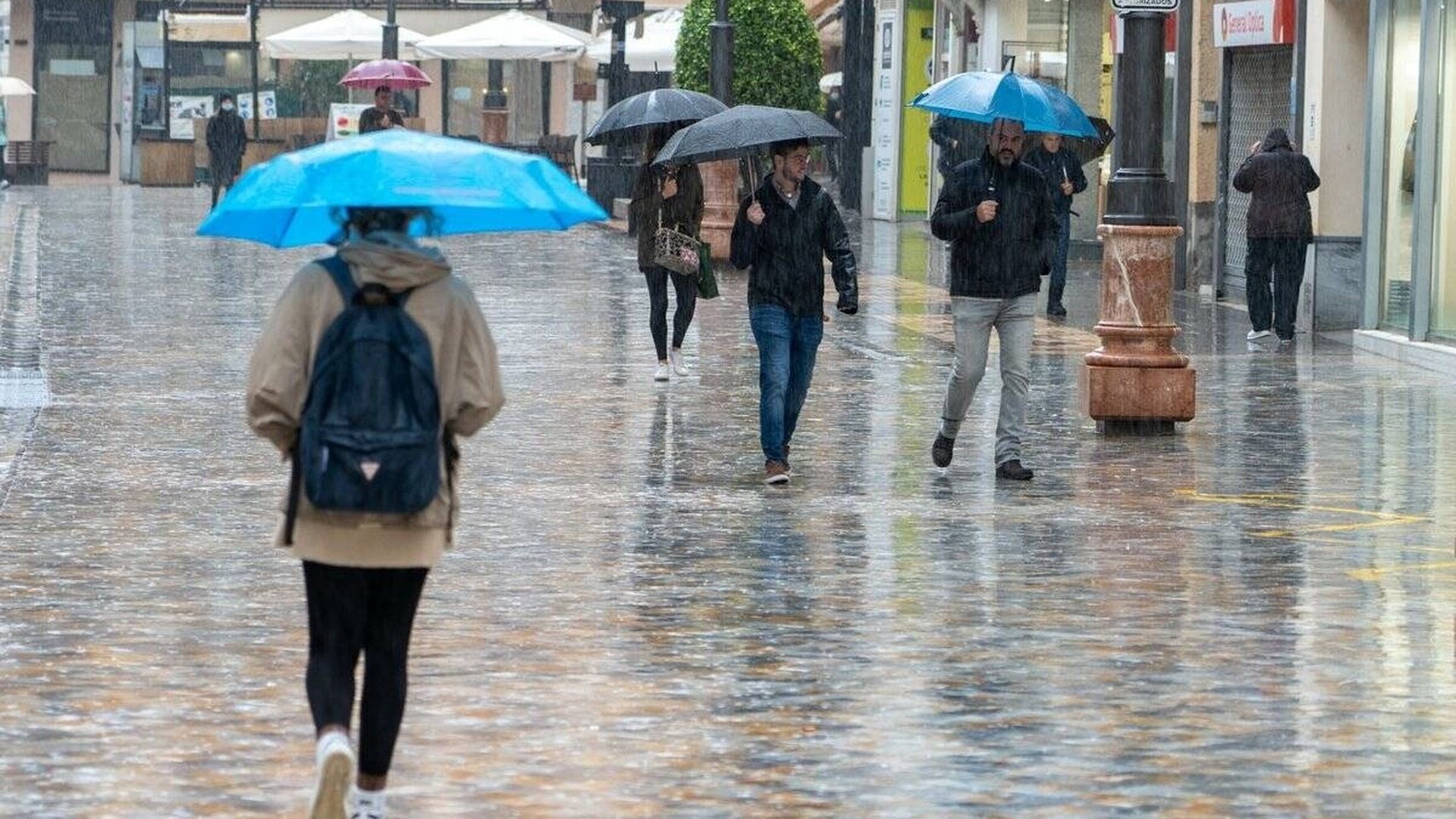 Varias personas paseando con paraguas por el centro de Cartagena bajo la lluvia